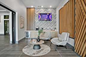 a lobby with chairs and a table and a tv on the wall