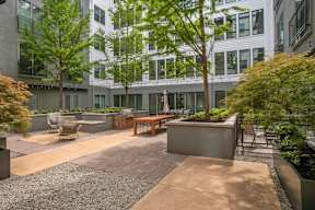 a courtyard with tables and chairs and trees in front of a building