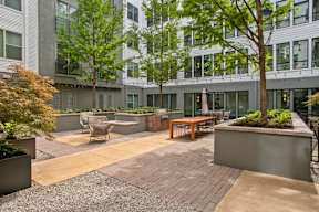 a courtyard with tables and chairs and trees in front of a building