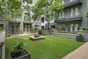 an open courtyard with grass and plants in front of a building
