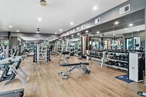 a gym with weights and cardio equipment on a wooden floor