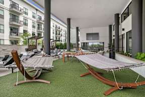 a courtyard with hammocks and lounge chairs in an apartment building