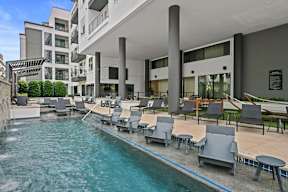 a swimming pool with lounge chairs and a building in the background