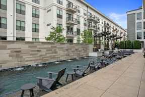 an outdoor patio area with tables and chairs next to a body of water