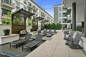 a group of lounge chairs on a patio in front of an apartment building