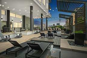 a rooftop patio with tables and chairs and a city in the background