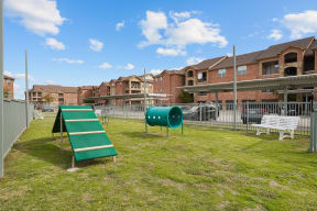 a green playground in a fenced in area with houses in the background