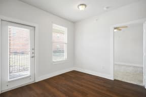 the living room of an apartment with white walls and wood flooring