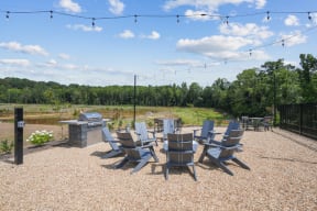 Outdoor firepit with chairs and tables surrounding it and a grill
