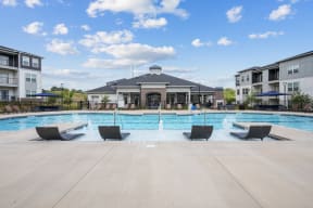 a large swimming pool with lounge chairs in front of the clubhouse