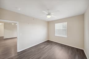 an empty living room with a ceiling fan and a window