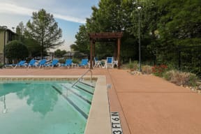 a swimming pool with blue chairs and a wooden structure