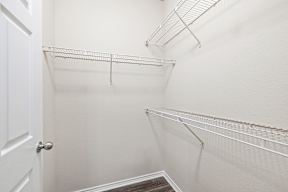 A white door is on the left of a hallway with two shelves.