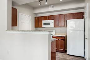 A kitchen with white appliances and brown cabinets.