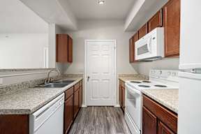A kitchen with white appliances and brown cabinets.