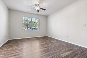 Empty room with a ceiling fan and wooden flooring.