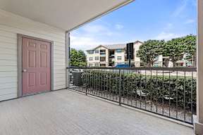 A balcony with a pink door and a black railing.