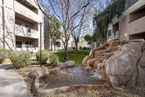 A small waterfall in a courtyard surrounded by rocks.at Vintage at Scottsdale, SCOTTSDALE, AZ