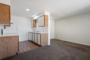 a living room with a kitchen and a carpeted floor