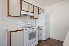 a kitchen with white appliances and wood flooring and a refrigerator