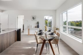 a dining room with a glass table and chairs and a kitchen with large windows