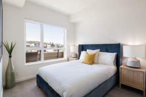 bedroom with a large window and a bed with white sheets and pillows