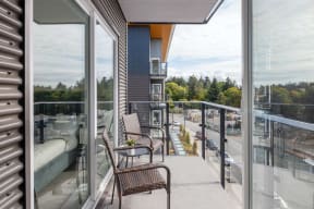 a balcony with two chairs and a table and glass doors
