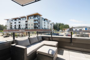 a patio with a couch and a table on a balcony in front of a building