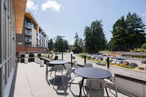 a patio with tables and chairs and a building with a parking lot