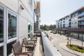 an apartment balcony with chairs and tables overlooking a city street