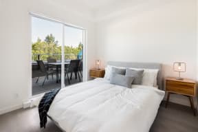 a bedroom with a bed and a sliding glass door to a balcony