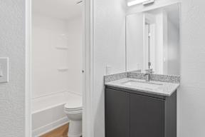A bathroom with a toilet, sink and mirror.