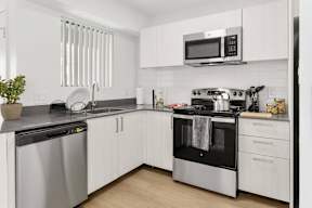 A modern kitchen with white cabinets and stainless steel appliances.