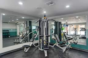 A gym with a mirrored wall and a variety of equipment.
