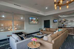 A living room with a grey couch, a brown couch, a coffee table, and a TV mounted on the wall.