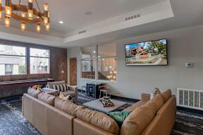 A modern living room with a large sectional sofa and a flat screen TV mounted on the wall.