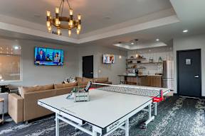 A ping pong table is in the middle of a living room.