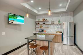 A modern kitchen with a bar stool and a television screen.