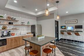 A modern kitchen with a bar stool and a fridge.