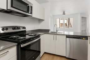 A modern kitchen with a black stove top oven and white cabinets.