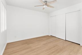 A room with a ceiling fan and wooden flooring.
