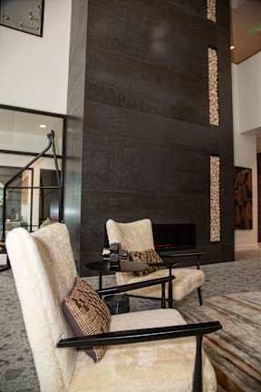Two chairs with cushions are in front of a fireplace.
