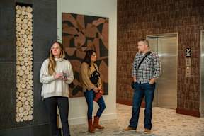Three people standing in front of a wall with a brown and black design.