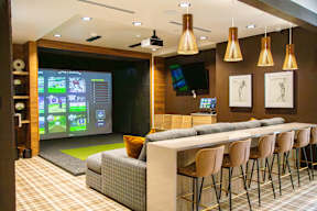 A modern bar with a large screen and comfortable seating.