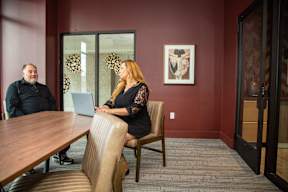 A woman in a black dress is sitting in a chair with a laptop on her lap.