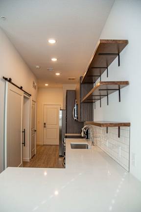A modern kitchen with a white countertop and a stainless steel refrigerator.