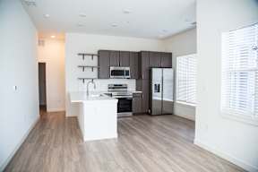 A modern kitchen with wooden floors and a white island.