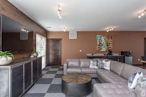 A living room with a grey couch and a black and white checkered floor.