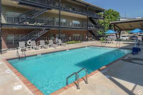 A swimming pool in front of a multi-story apartment building.