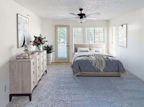 A bedroom with a bed, dresser, and a ceiling fan.